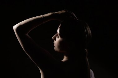 25 yaşında, esrarengiz bir kızın portresi. Karanlık bir arka planda el kaldırmış. Aydınlık ve kadın utangaçlığı..