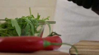 Bir şef domatesleri siyah eldivenli bıçakla kesiyor. Parlak bir mutfakta kesme tahtası, kamera hareketi, yavaş çekim, yakın çekim..