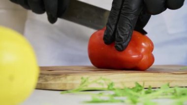 Aşçı kırmızı biberi doğrama tahtasındaki bıçakla ikiye böler, ağır çekimde..