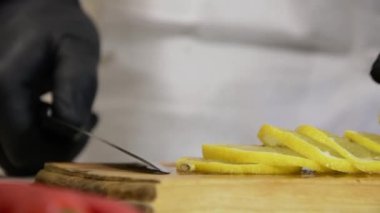 Aşçı kesme tahtasından ince dilimlenmiş bir limon topluyor, yavaş çekim, kamera hareketi..