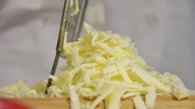 Mutfaktaki aşçı pizzanın peynirini ince bir rendeyle ovuyor. Pişirme ve pişirme, hafif ton, yavaş çekim.