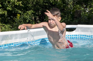 Çocuk yazın yüzüyor ve havuza dalıyor, su sıçrıyor. Açık hava sporları.