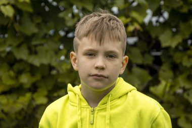 10 yaşında bir çocuğun sokak portresi. Ciddi bir yüzü ve modaya uygun bir saç kesimi var. Kavram: yakında okula, yaz tatilinde kırsala, botanik bahçesine..