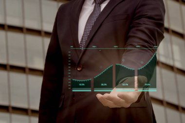 İş büyümesi. Bir işadamı satış verilerini ve ekonomik büyüme grafiğini bir gökdelenin zeminiyle karşılaştırır. İş stratejisi, finans ve bankacılık. Dijital pazarlama.