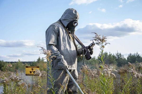 一名身着化学防护服的士兵在野外植被和天空的背景下 用云层检查受剂量计感染的放射性区域 — 图库照片