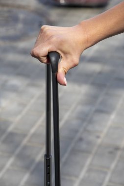 Seyahat valizinin sapını tutan güzel bir kadın el, yakın plan, seçici odaklanma. Konsept: bavulla seyahat, yakında tatile gitmek..