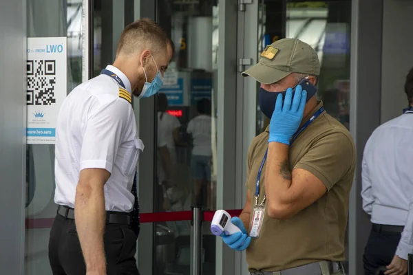 Lviv, Ukrayna, 22 Ağustos 2020, havaalanı girişinde, bir askeri sağlık görevlisi sivil pilotlar, editoryal görüntü, orta plan için temas olmayan termometreyle ısıyı ölçer..