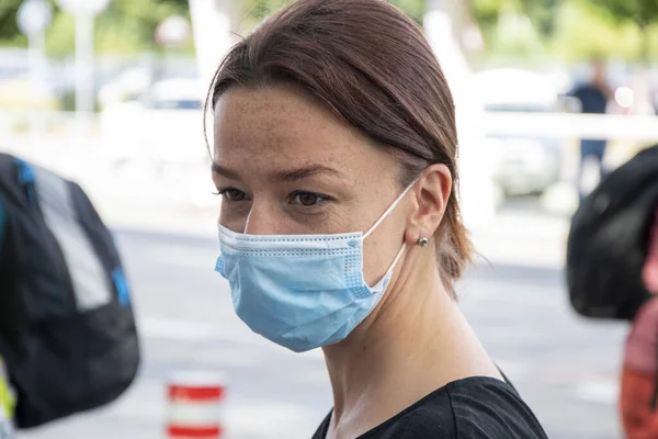 Street portrait of a woman in a medical mask, looking away, close-up, selective focus.