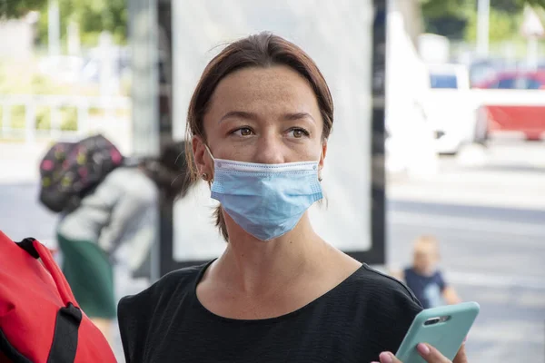 Street portrait of a woman in a medical mask, looking away, close-up, selective focus.