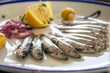 Küçük okyanus ringaları tabağın üzerine yarım daire şeklinde serilir, arka planda bir dilim limon, seçici bir odak noktası vardır..