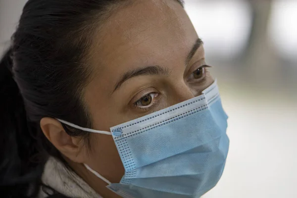 Portrait of a woman 35-40 years old with dark hair in a medical mask, tired appearance, close-up, selective focus. She may be a health worker or a nurse after an operation at the end of the day.