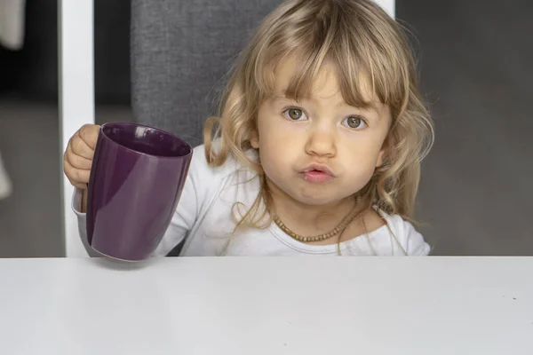 Uma Menina Está Sentada Cozinha Mesa Jantar Segurando Uma Caneca — Fotografia de Stock