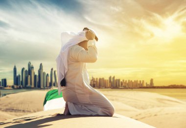 Arap adam kness BAE Çöl açık Dubai manzarası içinde oturan geleneksel Emirlikleri giysileri ile.