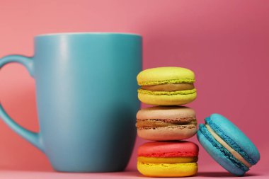 Mavi çay bardağı macaroons ile pembe arka plan üzerinde