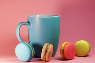 Mavi çay bardağı macaroons ile pembe arka plan üzerinde