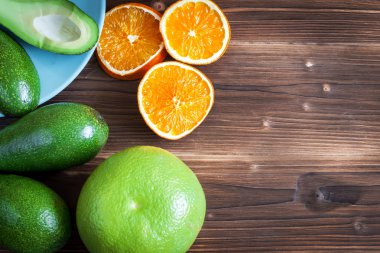 Üstten görünüm. Ahşap tahta ile dilimlenmiş renkli taze turuncu ve avokado greyfurt meyve. Siyah arka plan. Yaz arka plan.