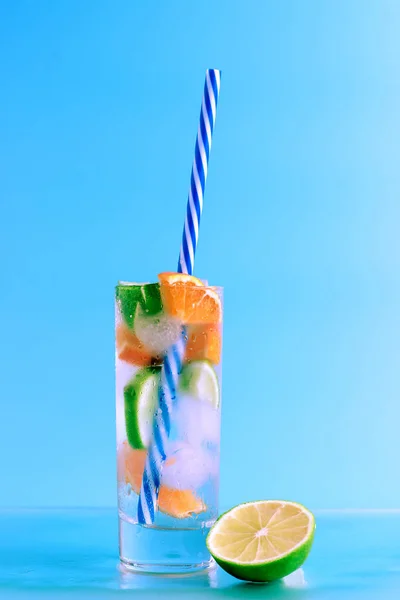 Fresh cocktail with lime, orange and ice on blue background. Summer background. — Stock Photo, Image