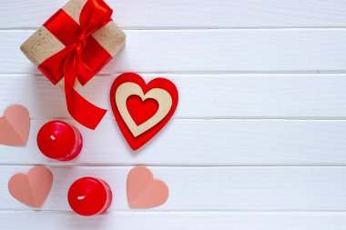 Ahşap beyaz arka plan kırmızı kalpler, hediyeler ve mum. Sevgililer günü kavramı. Üstten görünüm.