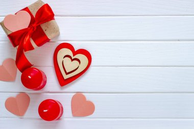 Ahşap beyaz arka plan kırmızı kalpler, hediyeler ve mum. Sevgililer günü kavramı. Üstten görünüm.
