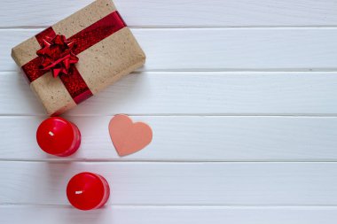 Ahşap beyaz arka plan kırmızı kalpler, hediyeler ve mum. Sevgililer günü kavramı. Üstten görünüm.