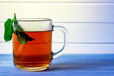 Beyaz ahşap arka plan üzerinde bardak yeşil çay nane yaprakları.