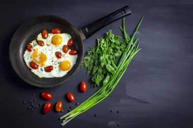 sahanda yumurta tava ve metin için yer ile koyu arka plan üzerinde taze soğan domates ile. Üstten Görünüm.