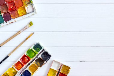 Beyaz ahşap arka planda eski boyalar ve fırçalar