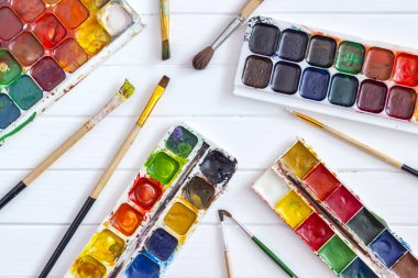 Beyaz ahşap arka planda eski boyalar ve fırçalar