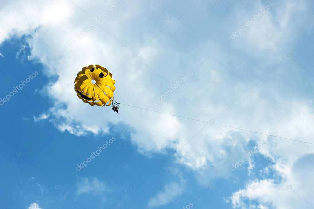 Two people are gliding using a parachute on the background of the blue sky. Summer background.