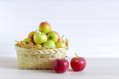 Ahşap beyaz masa üzerinde elma ile sepet, beyaz arka planda yalıtım.