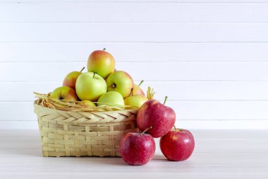 Ahşap beyaz masa üzerinde elma ile sepet, beyaz arka planda yalıtım.