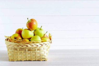 Ahşap beyaz masa üzerinde elma ile sepet, beyaz arka planda yalıtım.