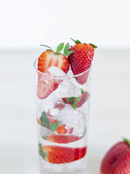 Strawberry in font of cocktail with ice isolated on white background with strawberry on top