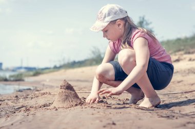 Sıcak ve güneşli yaz gününde kumlu bir göl plajda eğlenen sevimli genç kız. Nehir de oynayan genç kız. Çocuklar için yaz etkinlikleri.