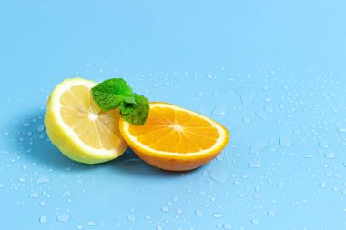 Su damlaları ile mavi bir arka plan üzerinde nane yaprakları ile portakal ve limon Dilimleri. Yaz serin su portakal dilimleri.