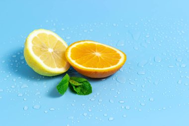 Su damlaları ile mavi bir arka plan üzerinde nane yaprakları ile portakal ve limon Dilimleri. Yaz serin su portakal dilimleri.