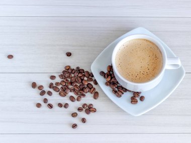 Kahve fincan ve kahve çekirdekleri, beyaz bir arka plan üzerinde izole yayıldı.