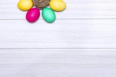 Paskalya yumurta beyaz ahşap zemin üzerinde pastel renklerde boyanmış.