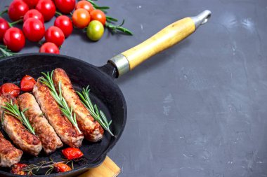 Siyah taş zemin üzerinde ızgara sosis ve kiraz domatesleri. Üst manzara, düz uzanma.