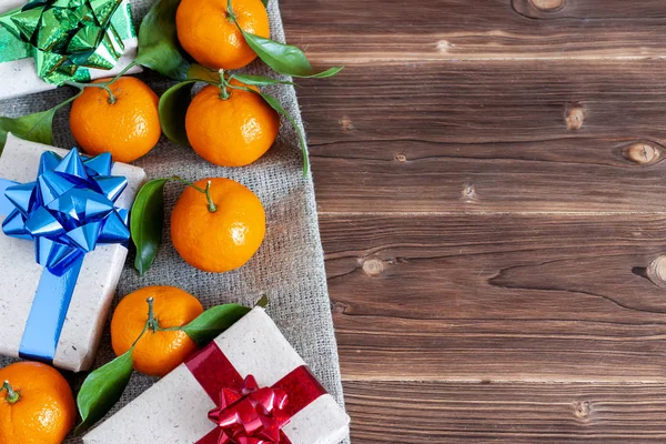 Christmas gift box on a dark background and tangerines. New Year\'s attributes.