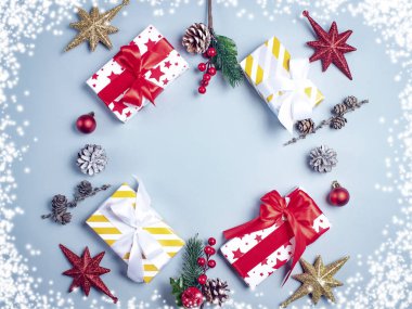 Mavi arka planda Noel hediyeleri ve kenarlarda kar, üst manzara.