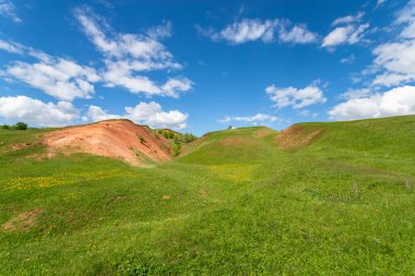 Bulutlu mavi gökyüzüne karşı yeşil tepeler