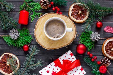 Bir fincan kahveyle Noel süslemesi, thuja dalları, koniler ve hediyeler.