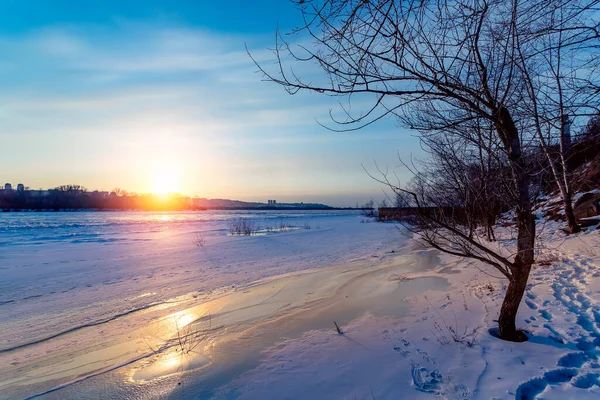 Schöner Wintersonnenuntergang mit Bäumen im Schnee und gefrorenem Fluss. — Stockfoto