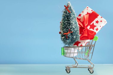 Mavi arka planda hediye kutusu ve alışveriş arabası. Yeni yıl hediyeleri. Yeni yıl indirimleri