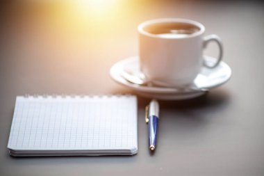 Masada buhar olan bir fincan kahve. Planlama ve güne başlama.