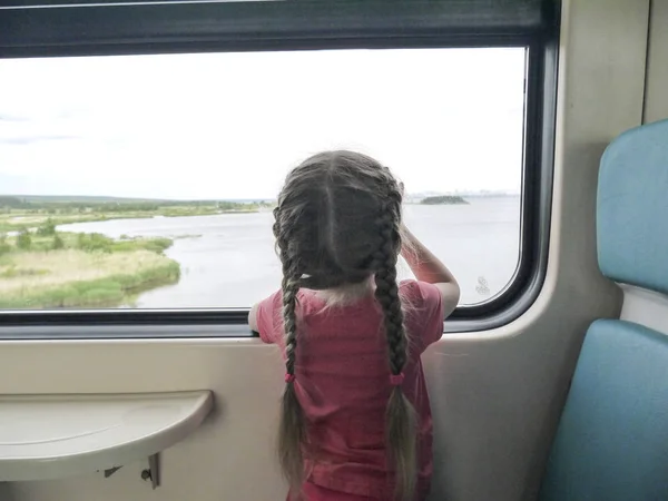 Ragazza Con Trecce Guarda Fuori Dal Finestrino Del Treno Foto Stock