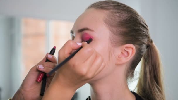 Maquillaje artista aplicación de productos de maquillaje con en un hermoso modelo en el estudio antes de la sesión de fotos — Vídeos de Stock