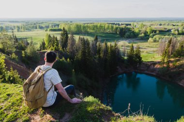 Genç turizm sırt çantası konumu güzel Kanyon kenarına olan adam ve zaferle ellerini kaldırdı. Dağın tepesine kadar ulaşan ve yukarı silah outstretching erkek uzun yürüyüşe çıkan kimse. Arka arkadan görünüm.