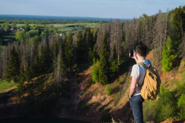 Elleri cebinde, yakışıklı sakallı adam uzakta göl kenarında duran arıyorum. Güneş gözlüğü ve moda kıyafetler giyen genç adam keşfetmek dünya, şık serin portre mans